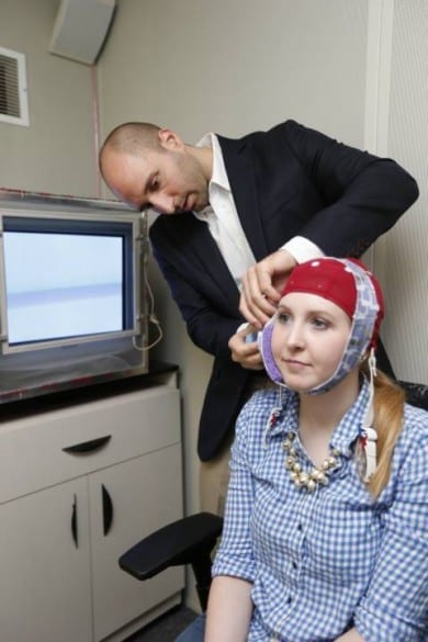 Robert Reinhart applies the electrical stimulus to subject Laura McClenahan. After 20 minutes the headband is removed and the EEG cap will capture readings of her brain as she executes the learning task. (John Russell / Vanderbilt University)