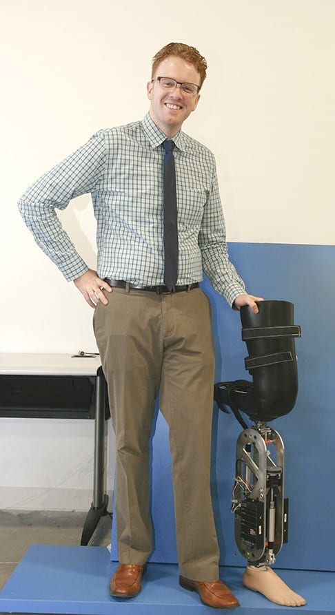 Dr. Robert Gregg stands next to a robotic leg that was designed by UTDesign students and is similar to the one reported in his research.