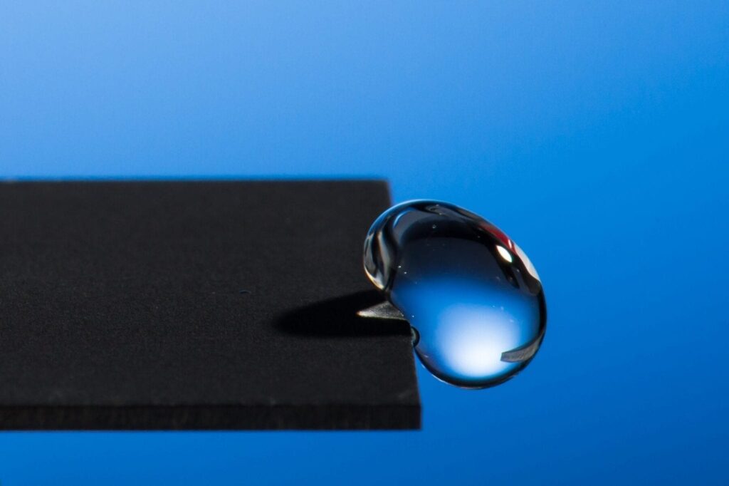 Professor Chunlei Guo has developed a technique that uses lasers to render materials hydrophobic, illustrated in this image of a water droplet bouncing off a treated sample. Photo by J. Adam Fenster / University of Rochester