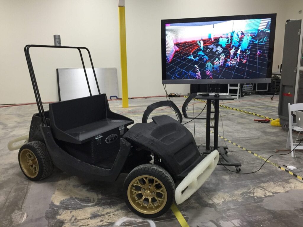 Researchers at the University of Michigan will develop autonomous capabilities for this 3-D printed low-speed electric vehicle that's manufactured by Arizona technology company Local Motors. The screen in the background shows a laser scan of the room. Image credit: Local Motors