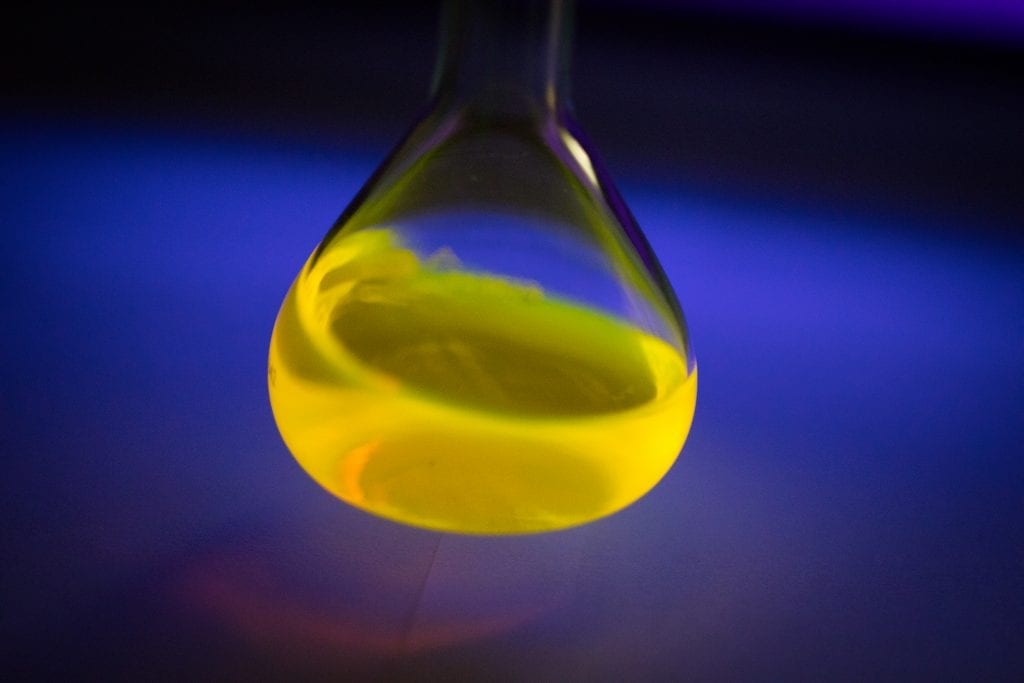 A glowing solution of BODIPY dye under a black light. A UB study shows that the dye has interesting chemical properties that could make it an ideal material for use in large-scale rechargeable batteries. Credit: Douglas Levere