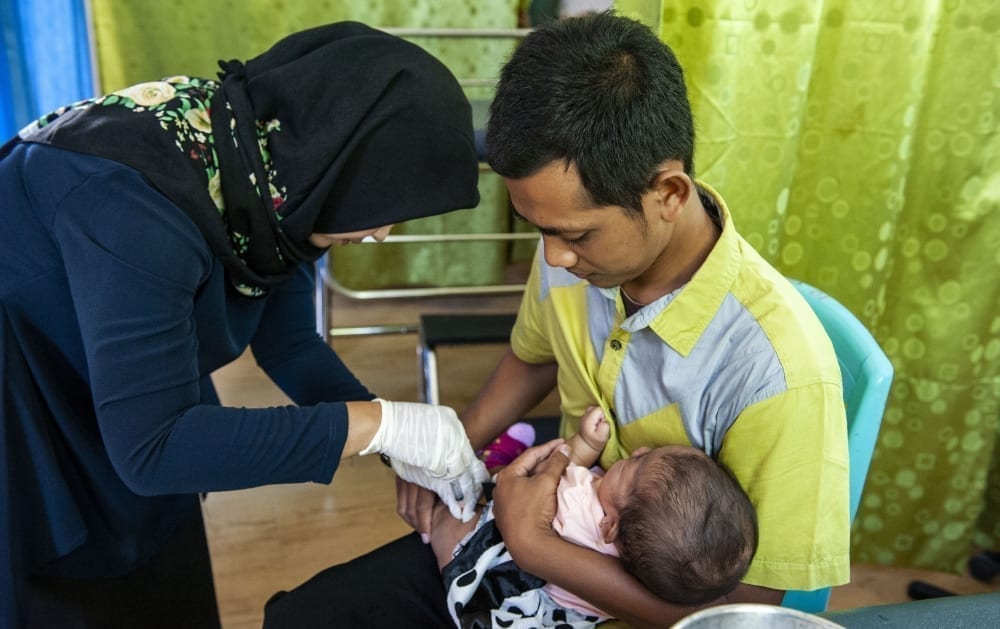 A nurse gives a baby an immunization at a healthcare clinic on the edge of the Gunung Palung National Park in West Kalimantan, Indonesia