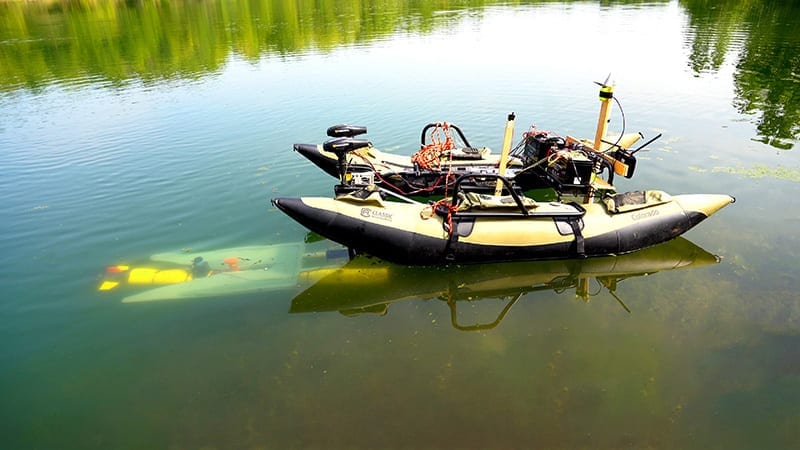 A yellow marine robot (left, underwater) finds its way to a mobile docking station to recharge and upload data before continuing a task. (Purdue University photo/Jared Pike)