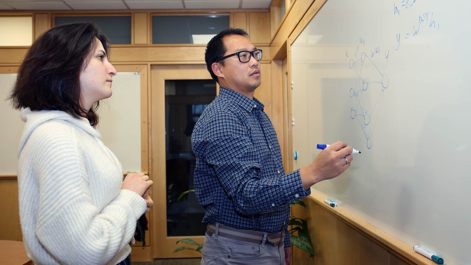 Cold Spring Harbor Laboratory Assistant Professor Peter Koo in his lab with graduate student Shushan Toneyan. Koo’s team studies how machine learning AI called deep neural networks (DNNs) work. He developed a new method for investigating how these DNNs learn and predict the importance of certain patterns in RNA sequences.