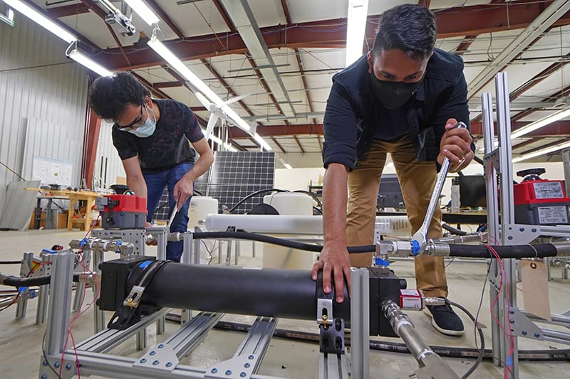 Graduate students Abhimanyu Das (left) and Akshay Rao adjust a piston tank, the key component to a new desalination process called “double-acting batch reverse osmosis.” (Purdue University photo/Jared Pike)