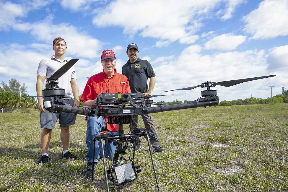 From left: FAU graduate student Anthony Davis; Warner A. Miller, Ph.D.; and collaborator Pedram Nimreezi, stand behind the large drone, which includes a network of a ground station, lasers and fiber optics. (Photo by Alex Dolce)
