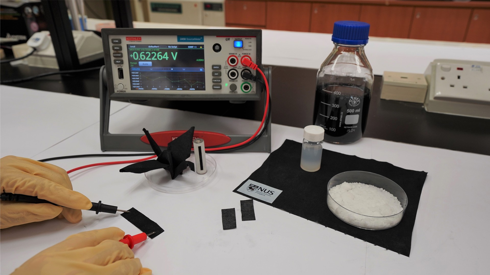 The new moisture-driven electricity generation device invented by NUS researchers capitalises on the difference in moisture content of the wet and dry regions of the carbon-coated fabric to create an electric current. Sea salt is used as a moisture absorbent for the wet region.