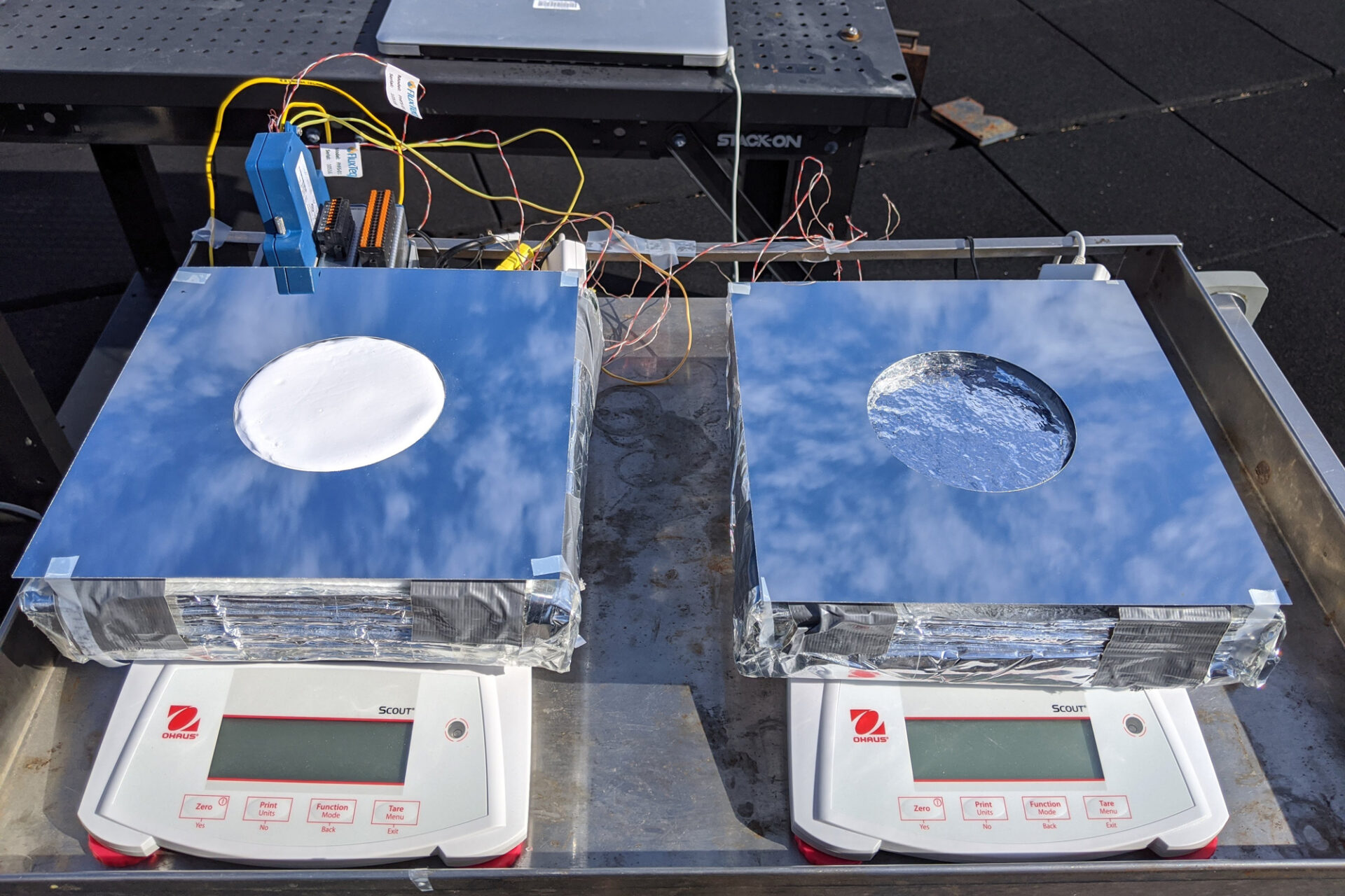 Caption:Two samples of passive cooling devices were tested on the roof of MIT's Building 1: On the left, a sample of the new system, combining evaporative cooling, radiative cooling, and insulation. On the right, a device using just evaporative cooling, for comparison testing. Credits:Photo: Courtesy of Zhengmao Lu