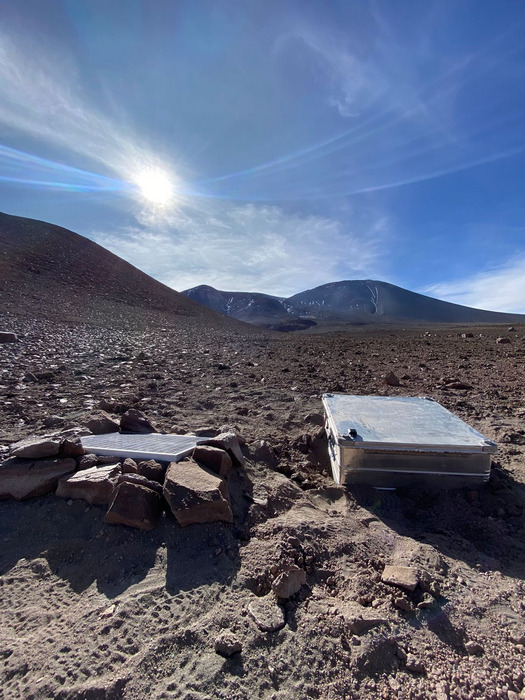The SO2 camera installation on Lascar Volcano, Chile. The camera is housed inside a protective metal casing, which also holds the battery for powering the instrument; a solar panel for battery charging is located to the left of the box. CREDIT Dr Thomas Wilkes