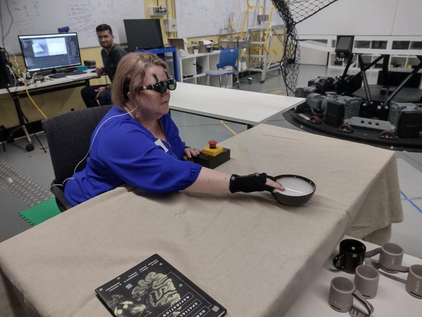 A research team member who is blind uses acoustic touch to locate and reach for an item on the table. Photo: Lil Deverell CC-BY 4.0